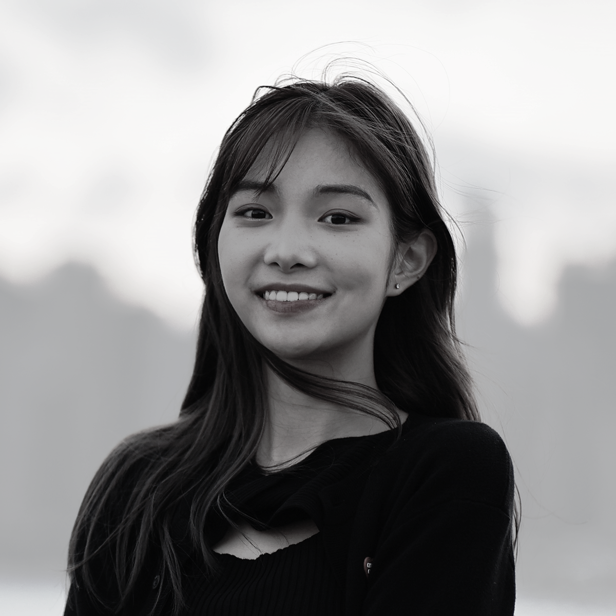 Black-and-white portrait of Katy, a Multimedia Designer, smiling next to the sea.